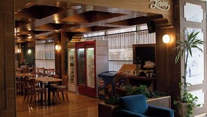 A cozy restaurant interior with wooden furniture, a seating area, and a counter. - Comodoro Hotel (Comodoro Rivadavia)