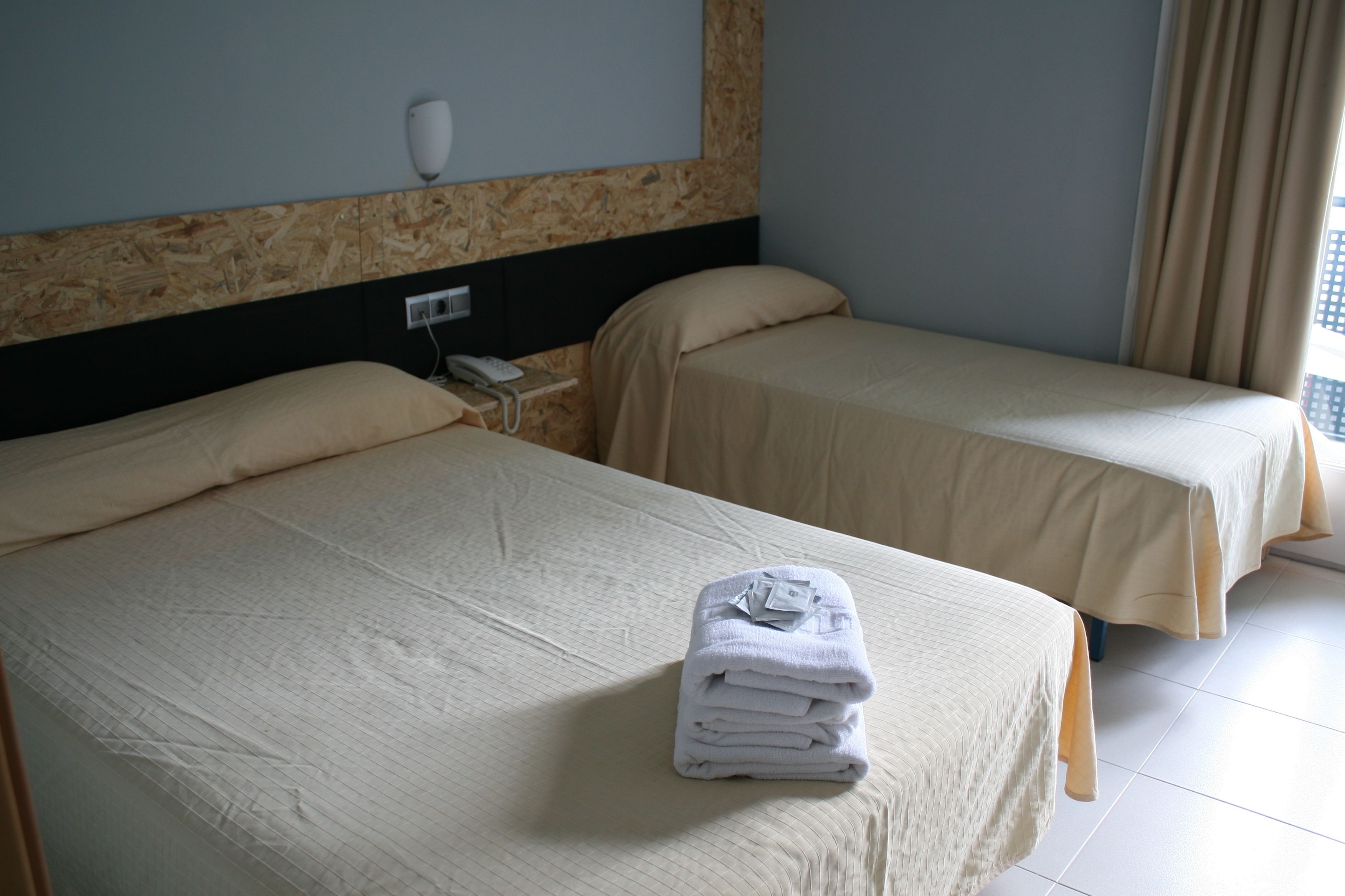 Une chambre d’hôtel avec deux lits, une table de chevet et un téléphone.