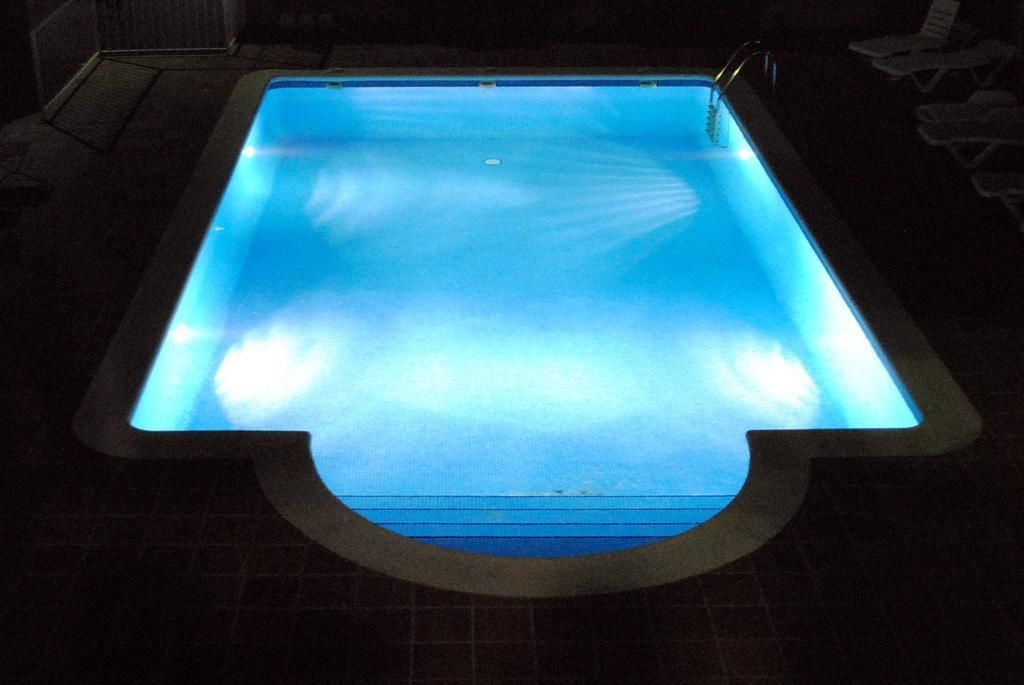 A rectangular swimming pool with a clear blue water surface and a lighted edge.