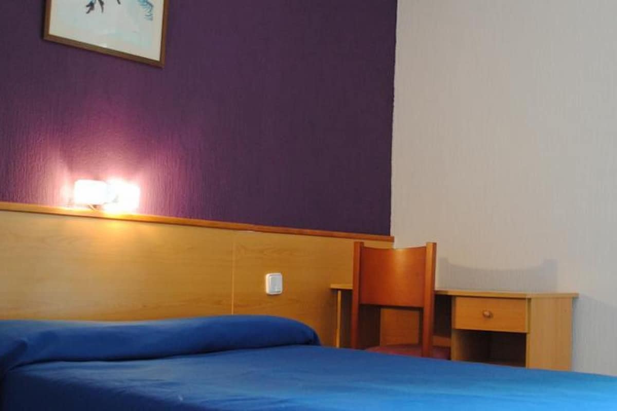 A hotel room with a bed, a desk, and a chair.
