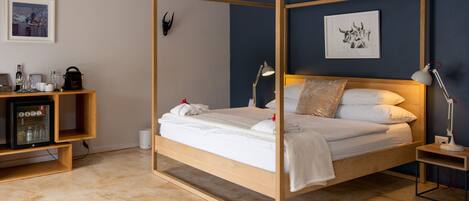 Una cama con dosel de madera, ropa de cama blanca y una mesita de noche con una lámpara.