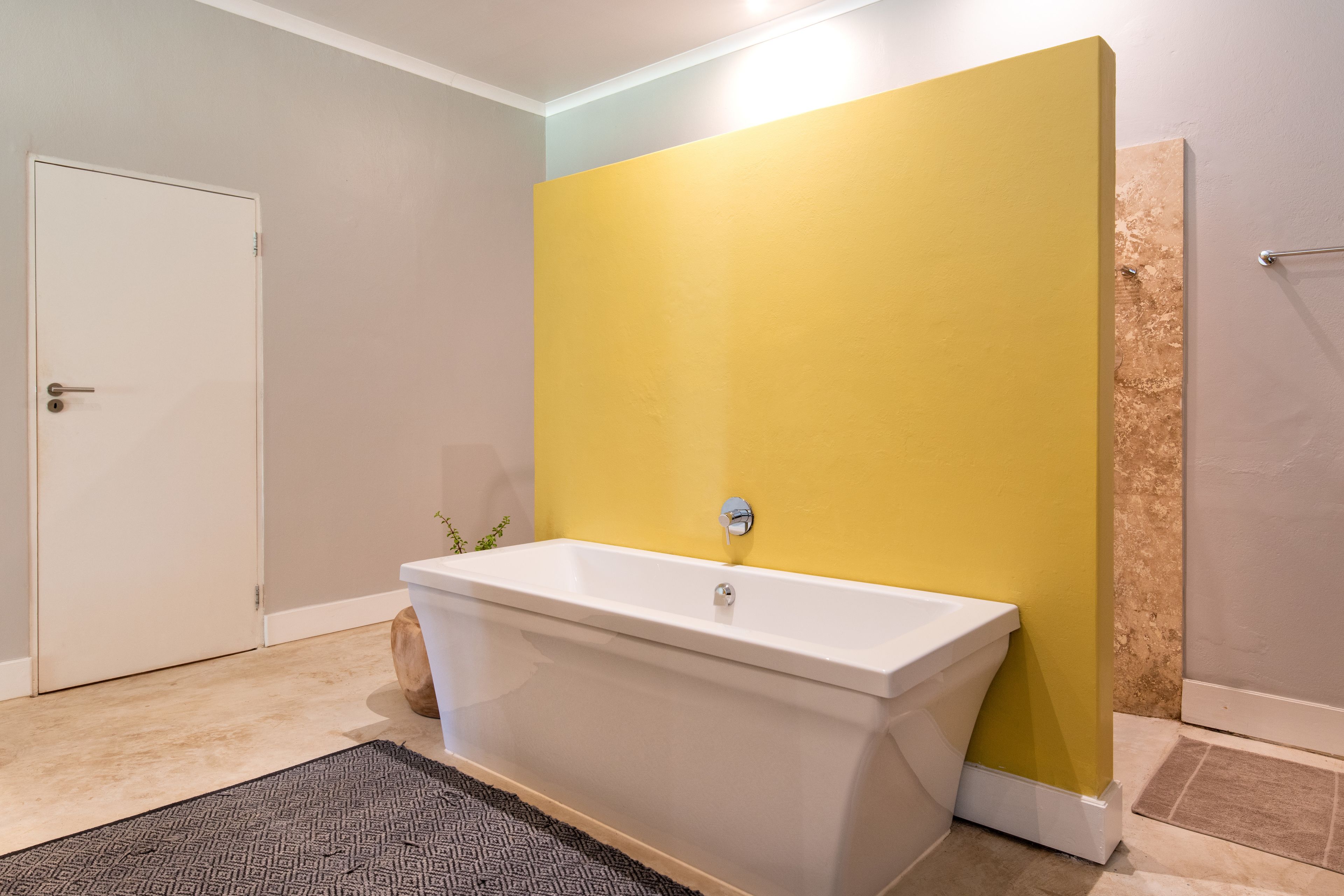 A bathroom with a bathtub, a white door, and a yellow wall.