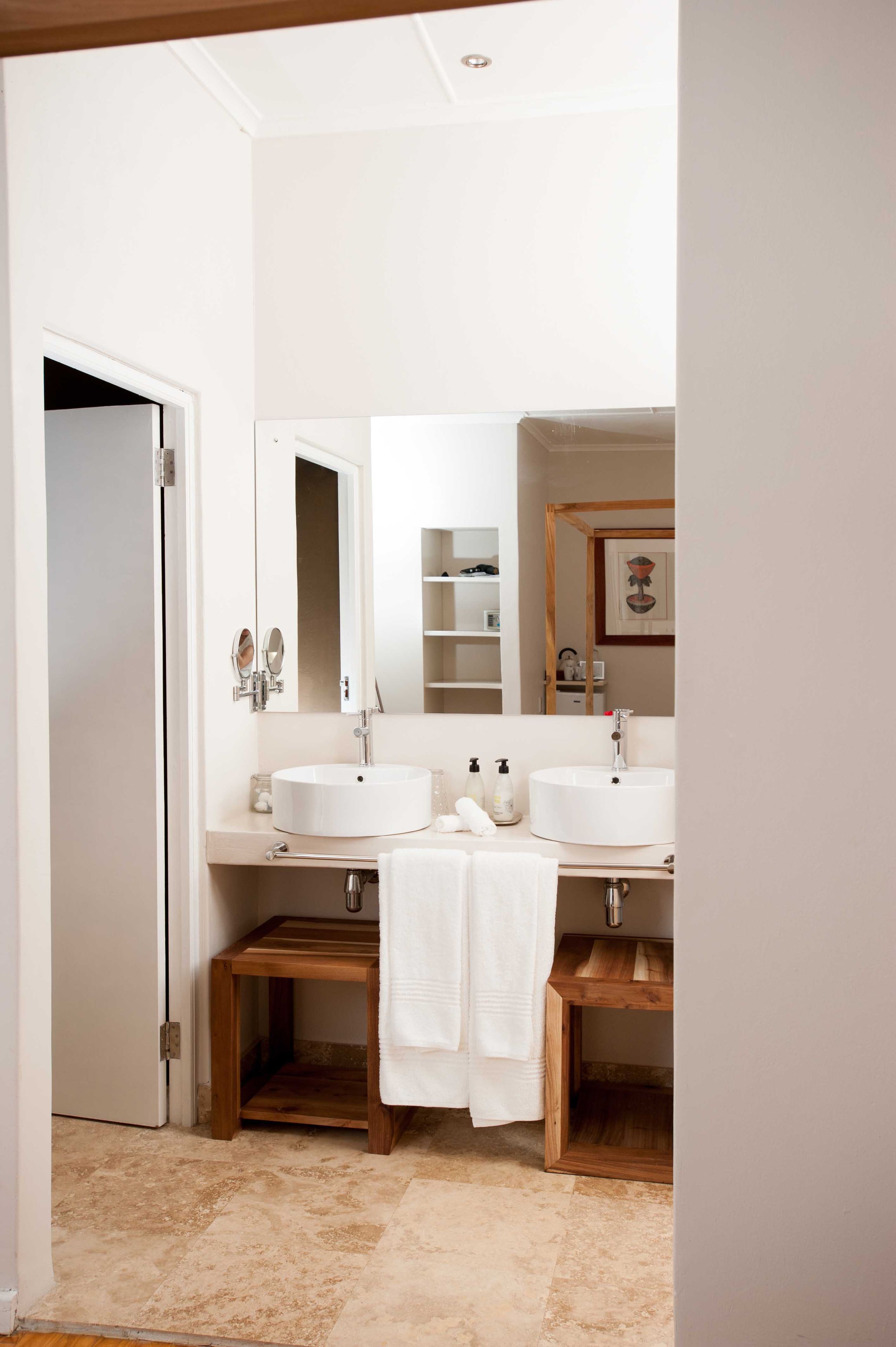 Un baño con dos lavamanos, un espejo y un banco de madera.
