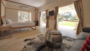 Un dormitorio moderno con cama, televisor y vistas al exterior.