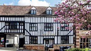 A traditional Tudor-style building with a black and white timber frame exterior, a sign reading "The White Hart Hotel," and a brick base. - The White Hart Hotel (St Albans)
