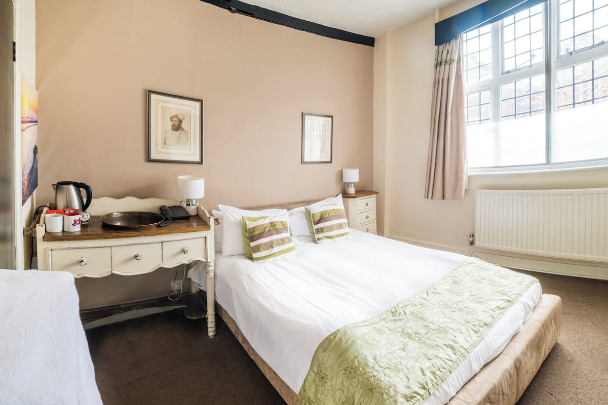 Une chambre d’hôtel avec un lit, une table de chevet, une lampe et un tableau encadré au mur.
