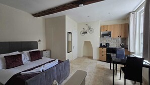 A bedroom with a bed, bedside table, and a small desk area with a chair. - The White Hart Hotel (St Albans)
