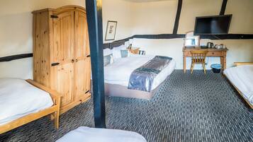 A hotel room with a bed, a desk, a chair, a wardrobe, and a television.