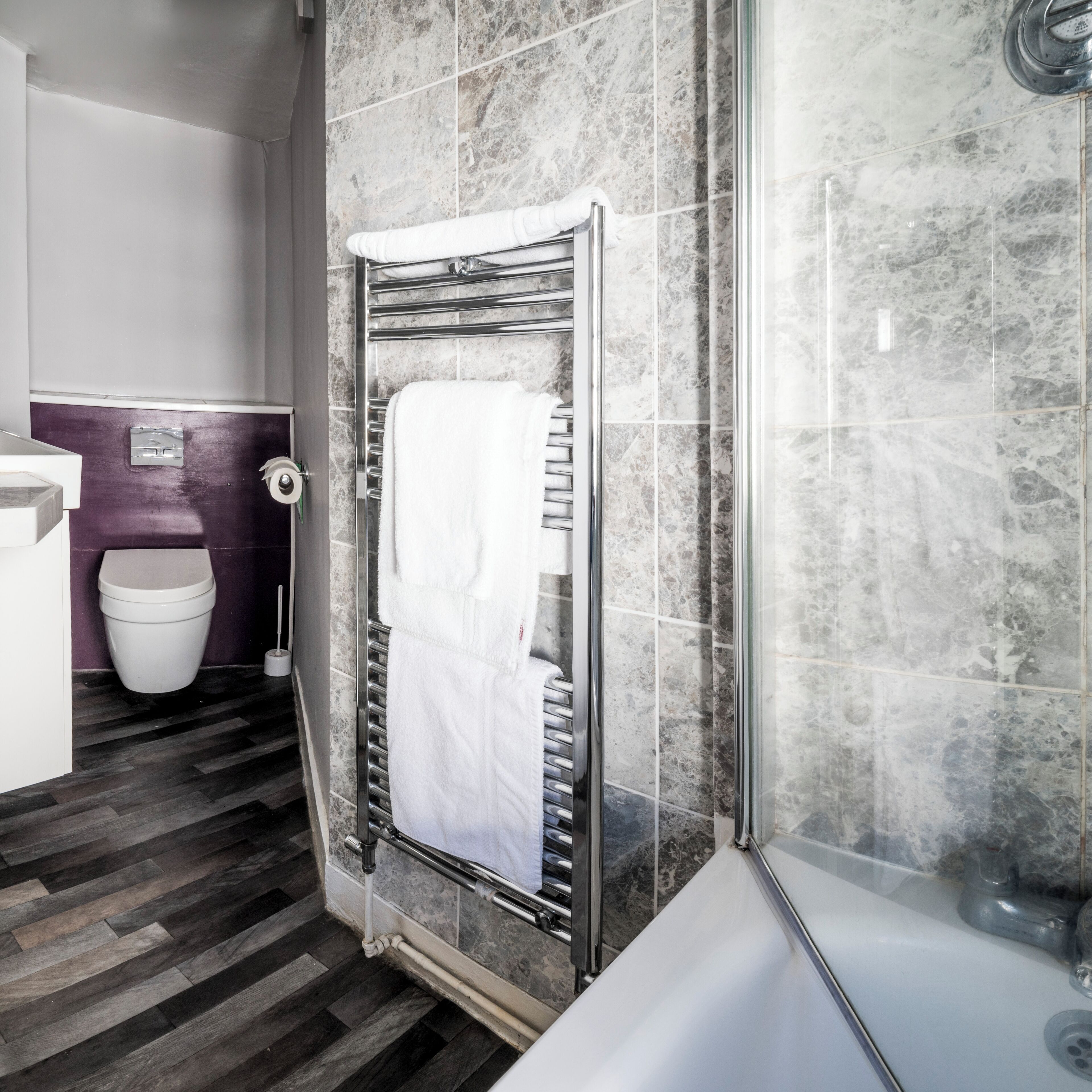 Ein modernes Badezimmer mit Dusche, Toilette und Handtuchhalter.