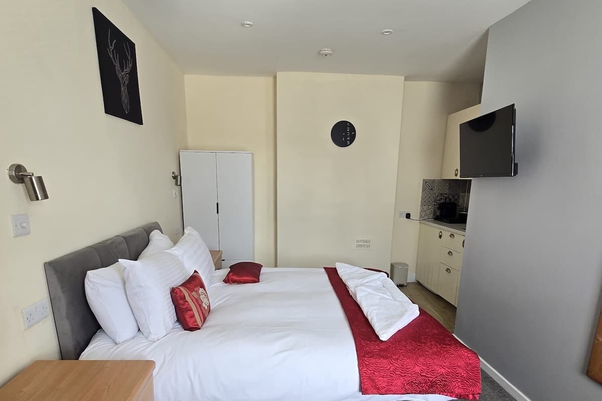 Une chambre à coucher avec un lit, une armoire, une télévision et une horloge au mur.