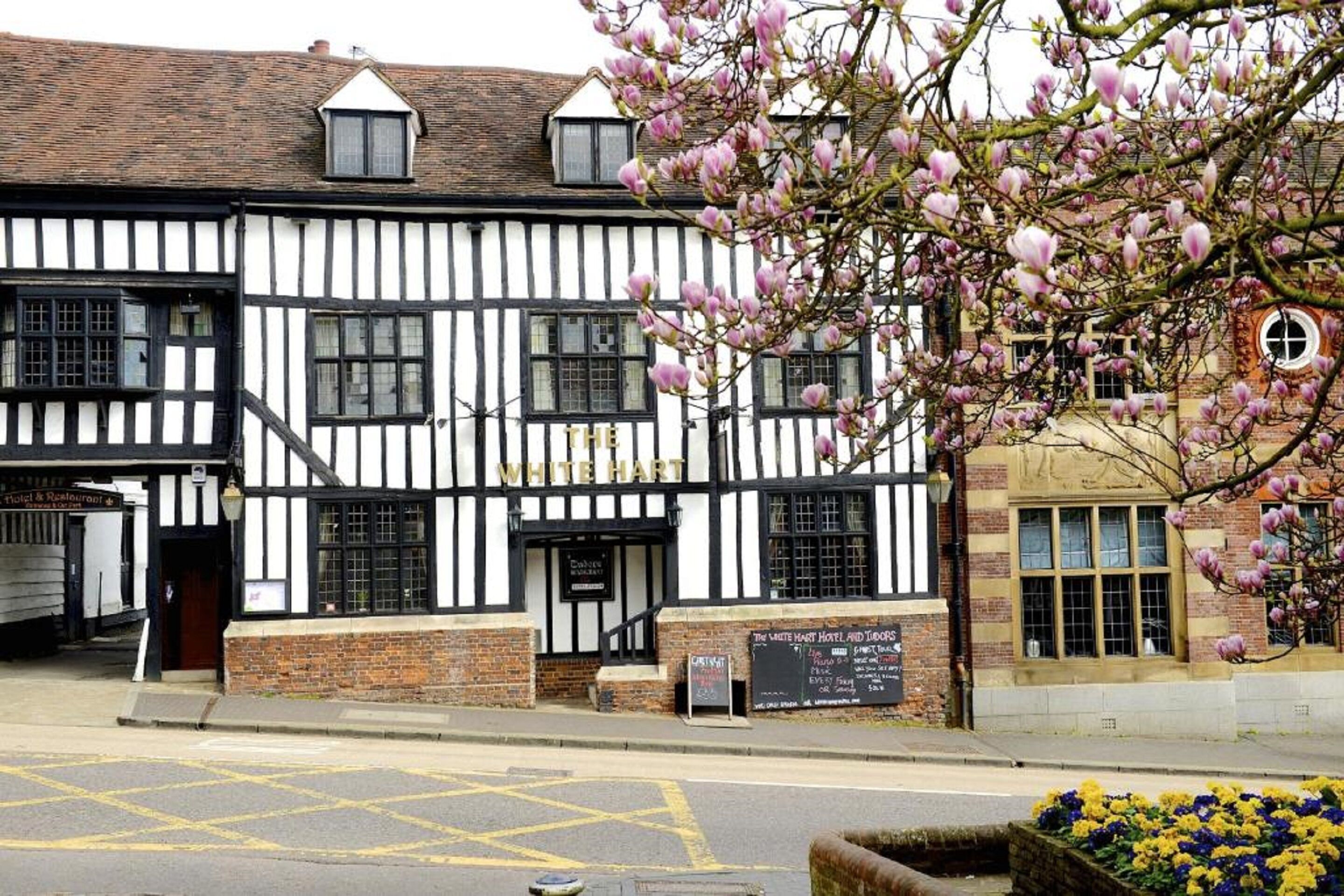 Een traditioneel gebouw in Tudorstijl met een bord waarop staat: 'The White Hart Hotel and Lodgings'.