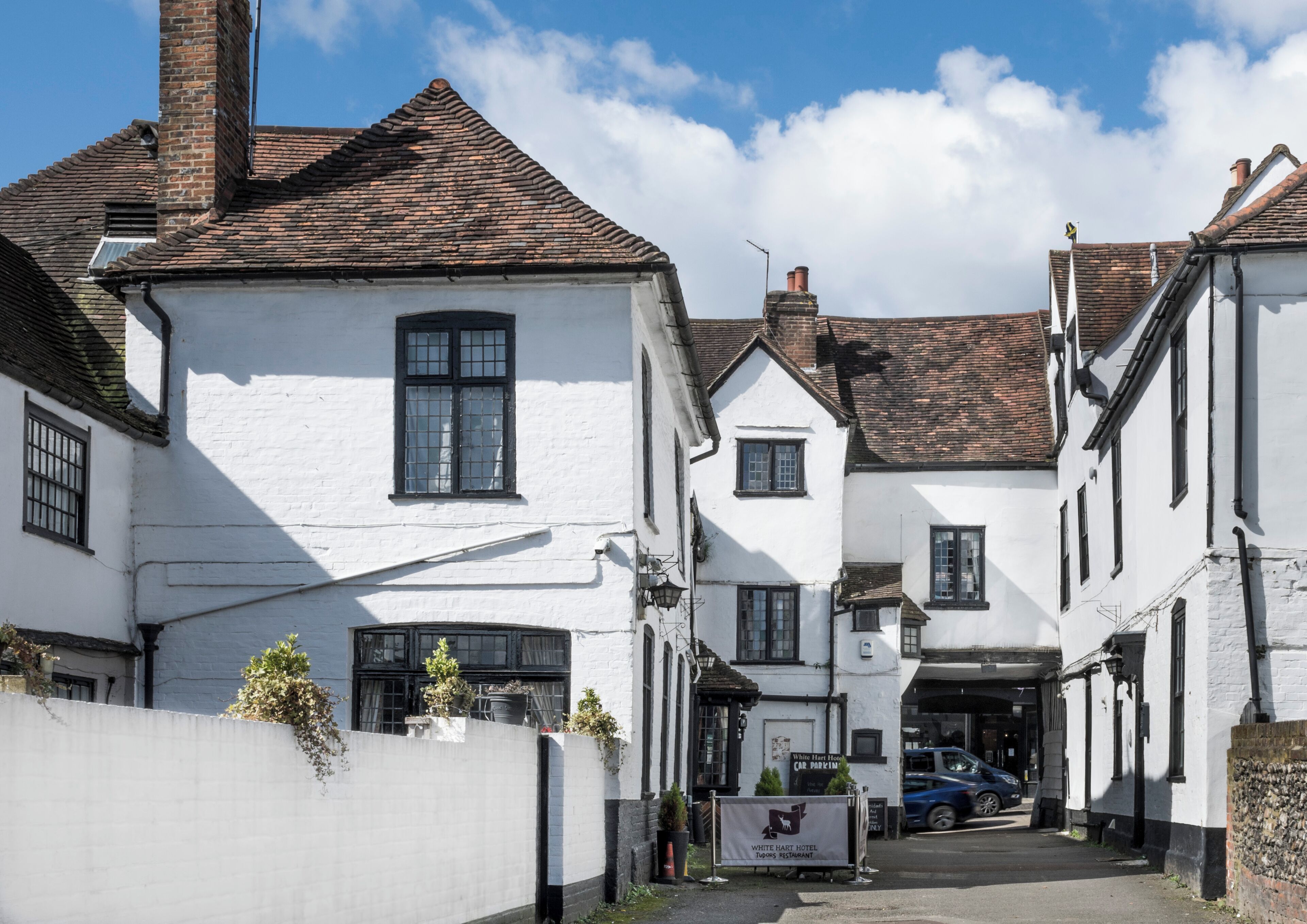 A traditional white building with a sign for the White Hart Hotel and a nearby restaurant.