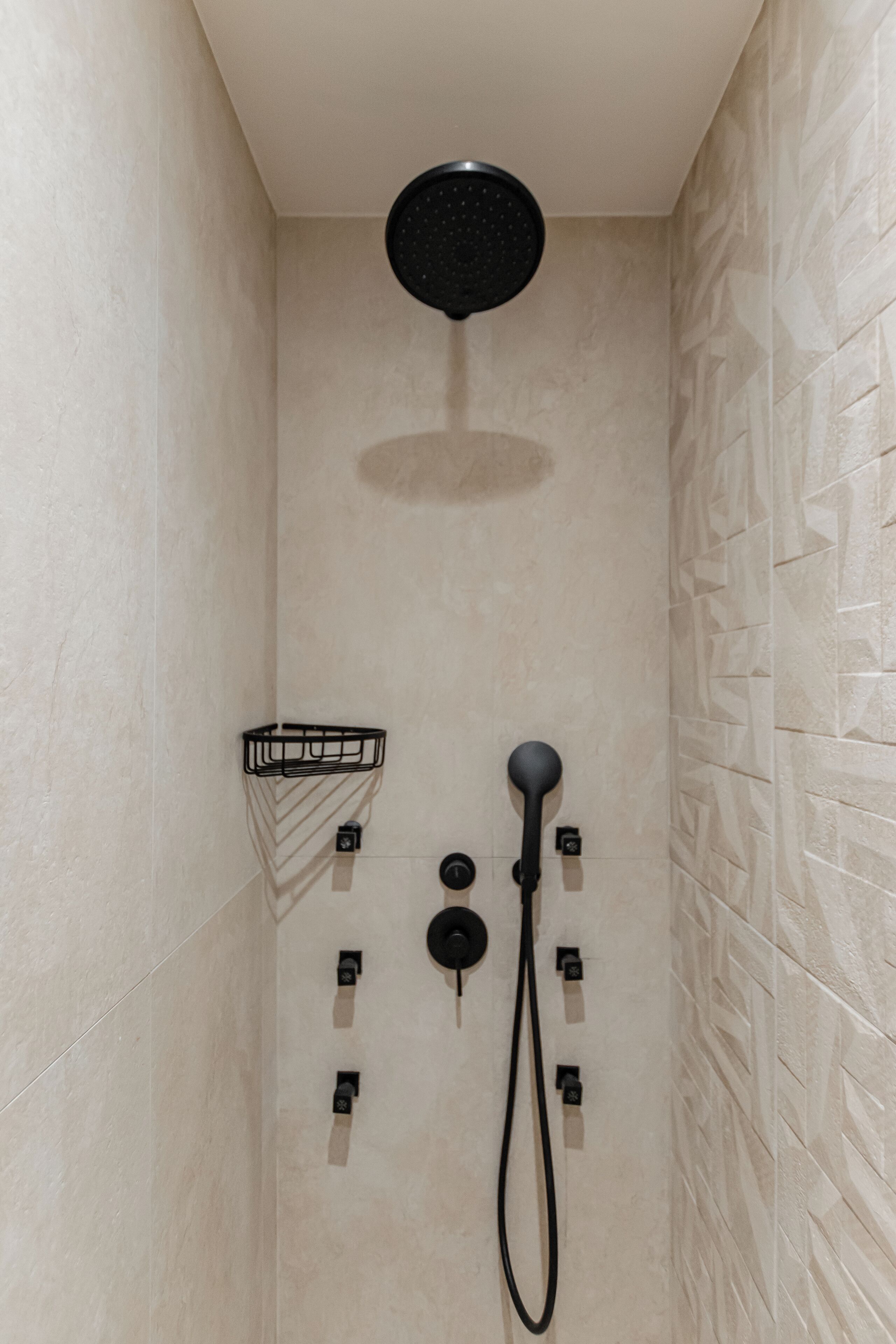 A shower with a roundhead showerhead, a handheld showerhead, and a wall-mounted control panel.