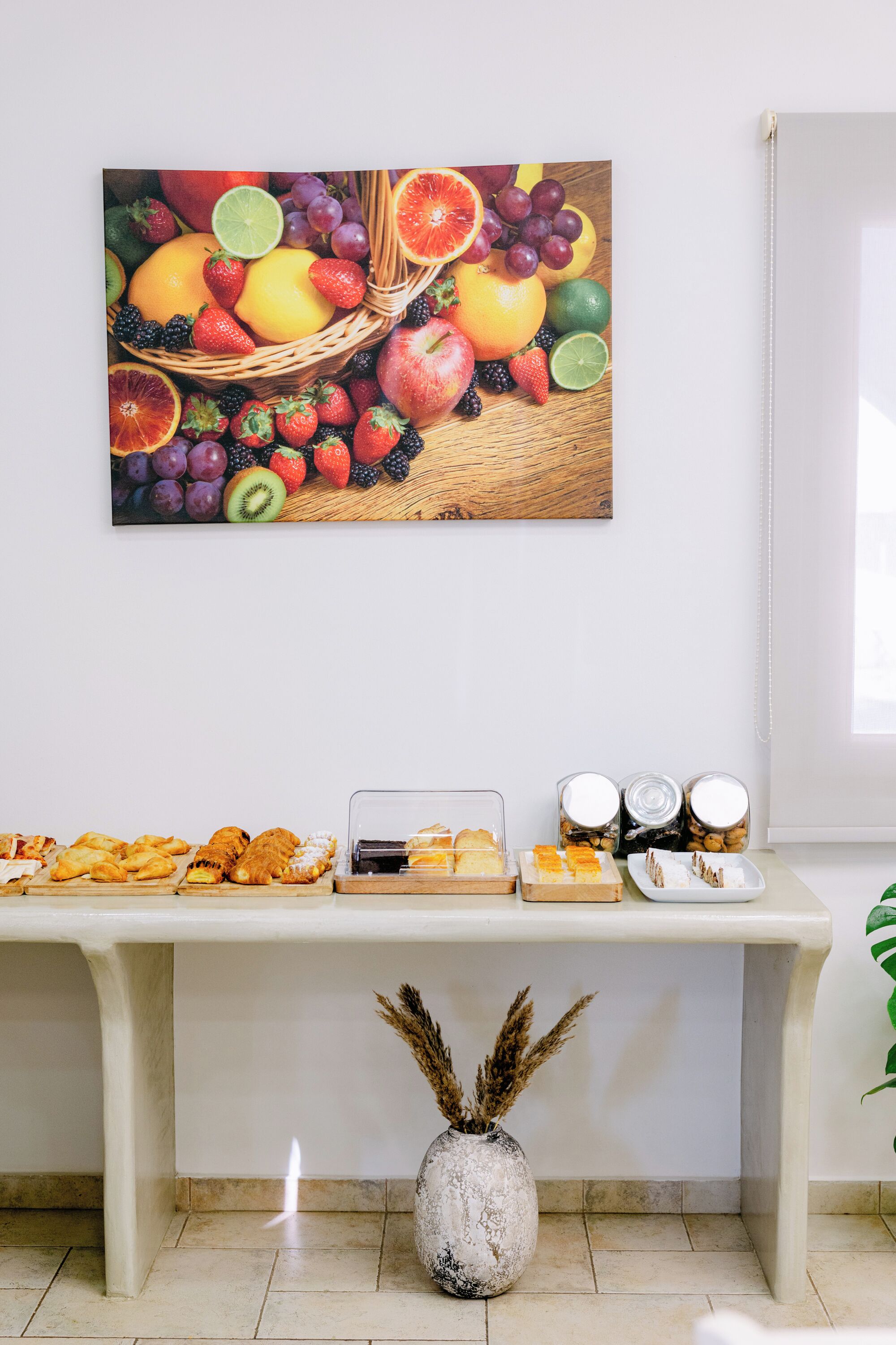 A buffet table with various pastries and a fruit basket on the wall.