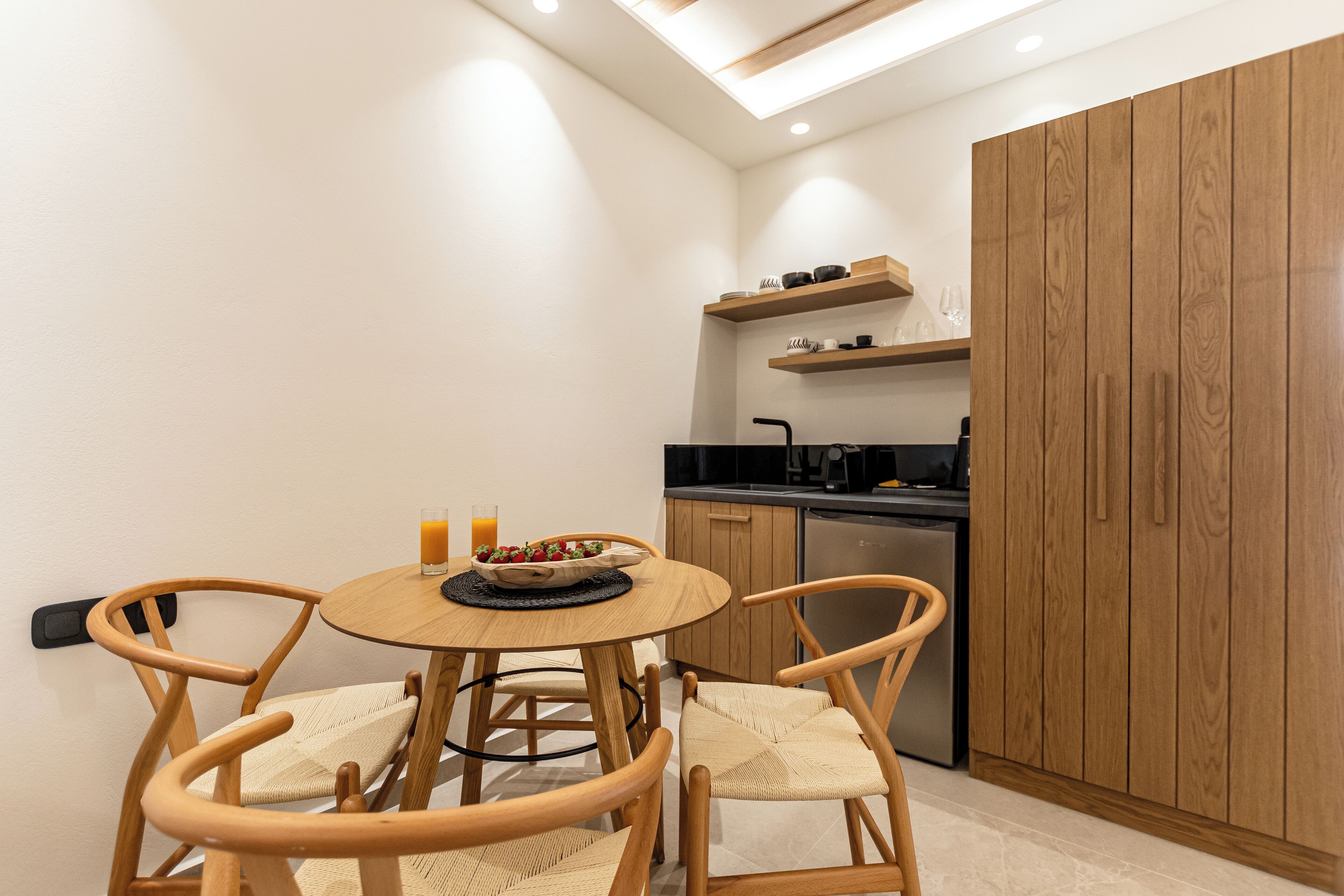 Una cocina compacta con armarios de madera, una mesa de comedor con cuatro sillas y un horno empotrado.