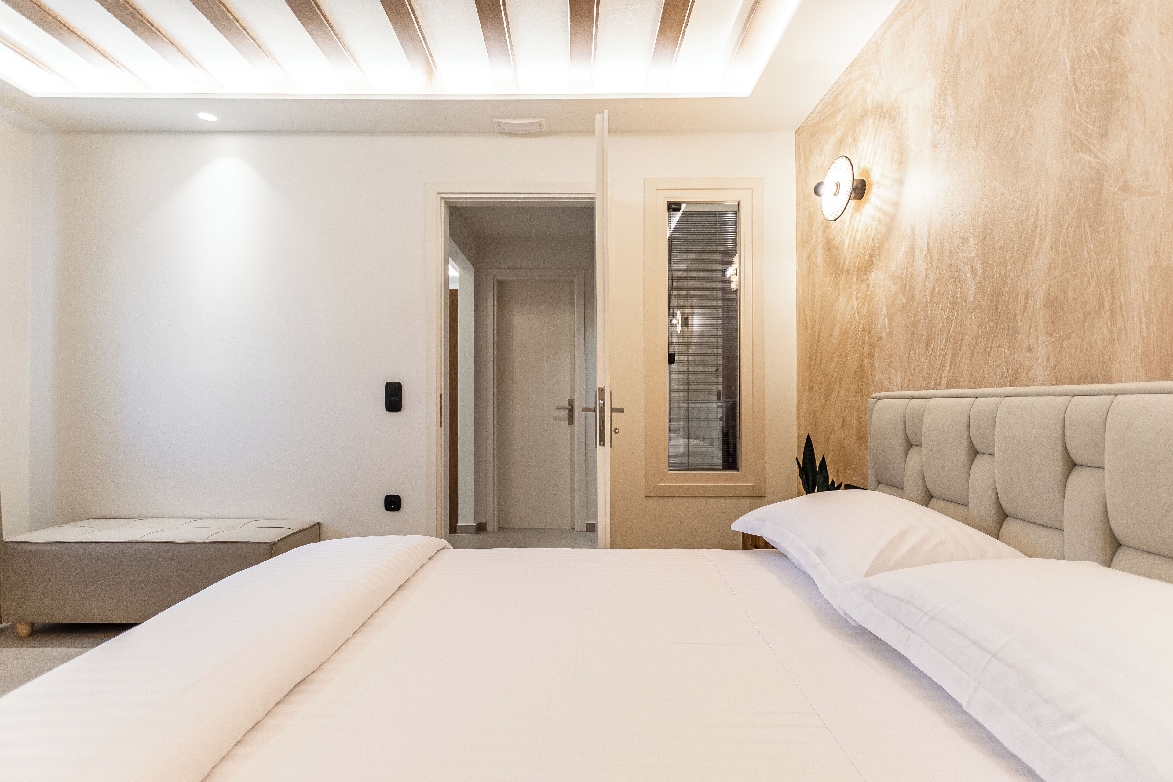 Un dormitorio moderno con una cama grande, una mesita de noche y una ventana con persianas.