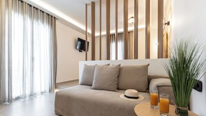 Una habitación de hotel moderna con un sofá, una mesita con vasos de jugo de naranja y una planta decorativa.