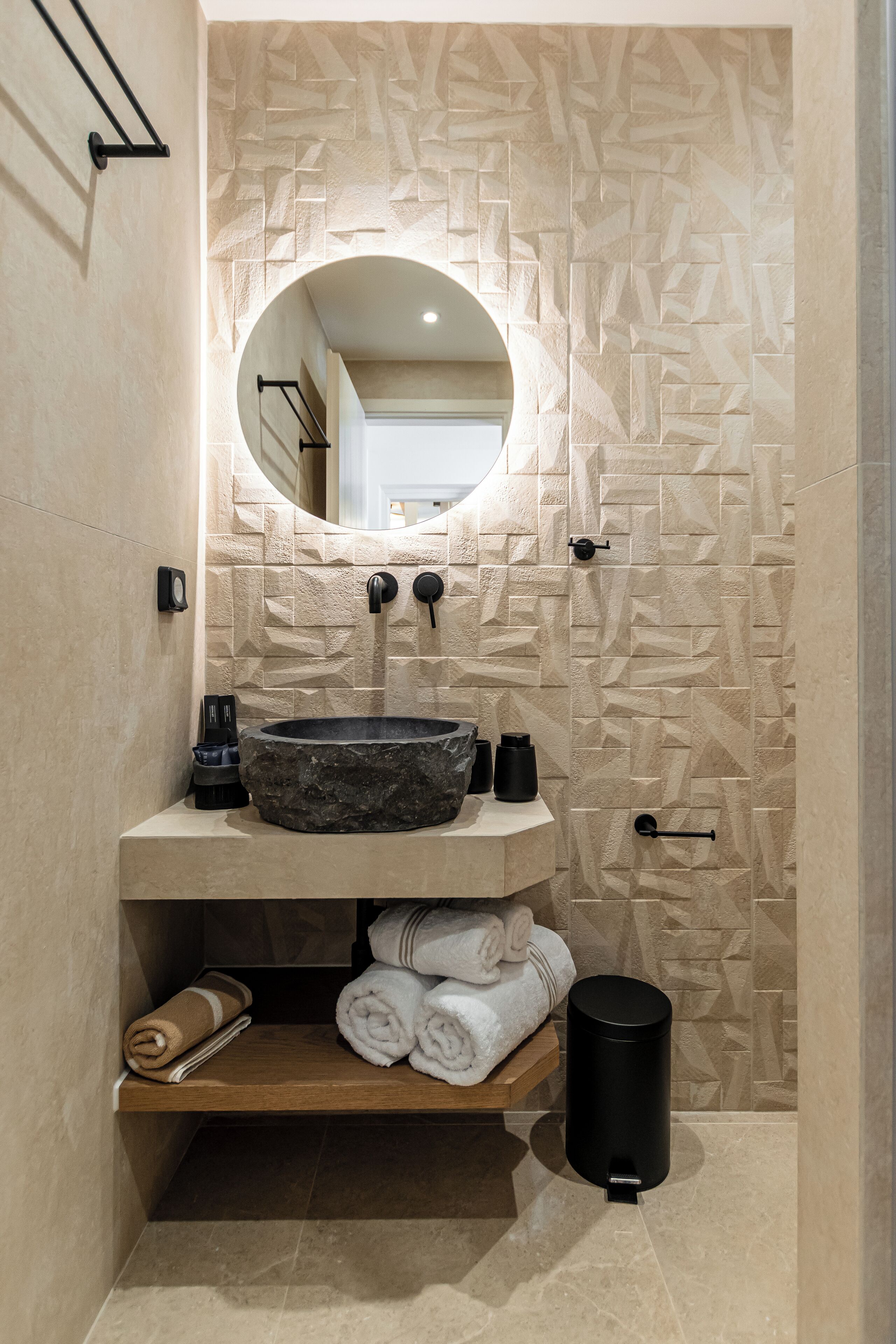 Un bagno con lavabo in pietra, uno specchio e un porta asciugamani.