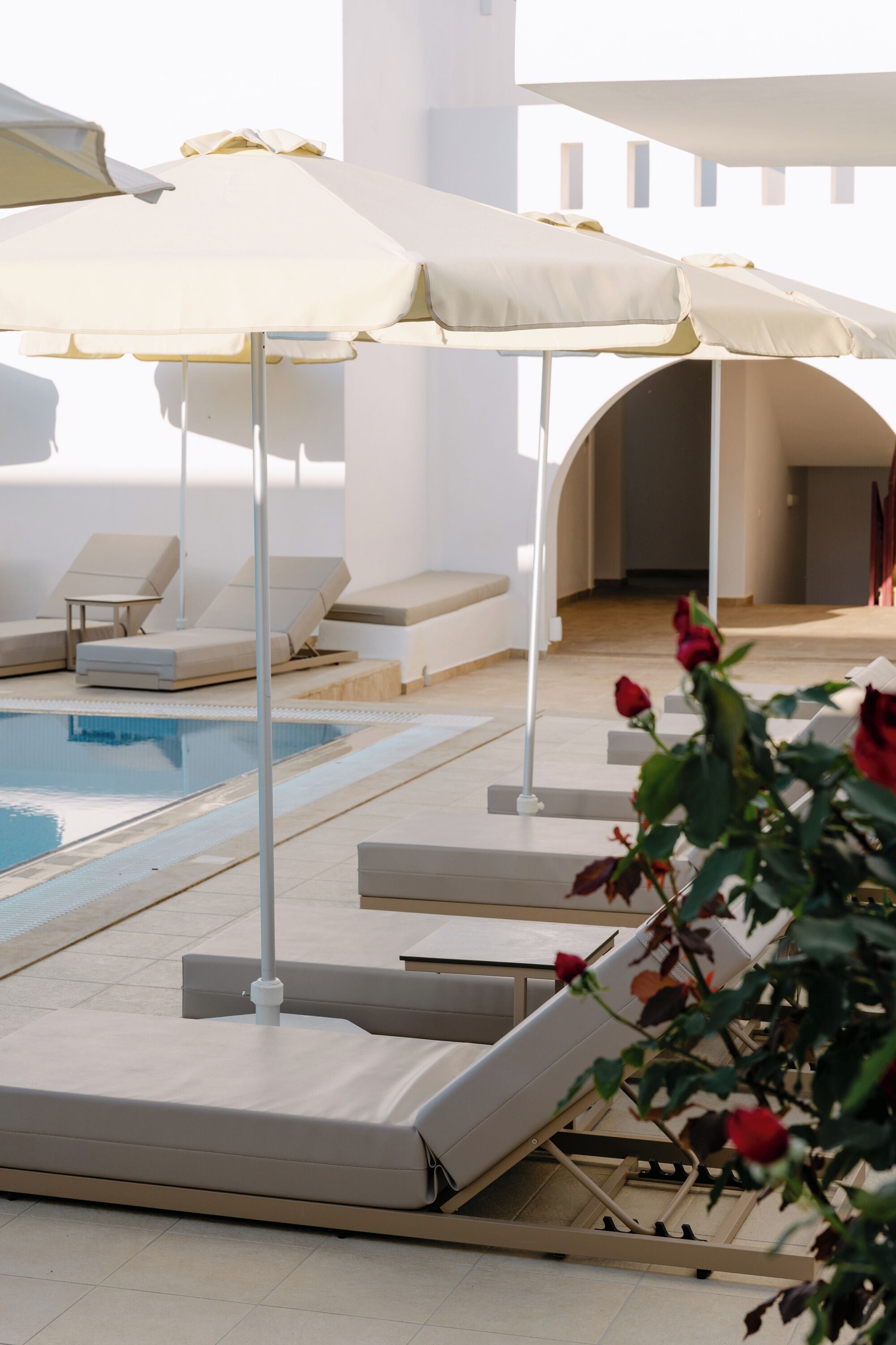 A pool area with lounge chairs and umbrellas.