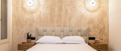 Un dormitorio moderno con una cama grande, vigas de madera en el techo y dos lámparas de pared.