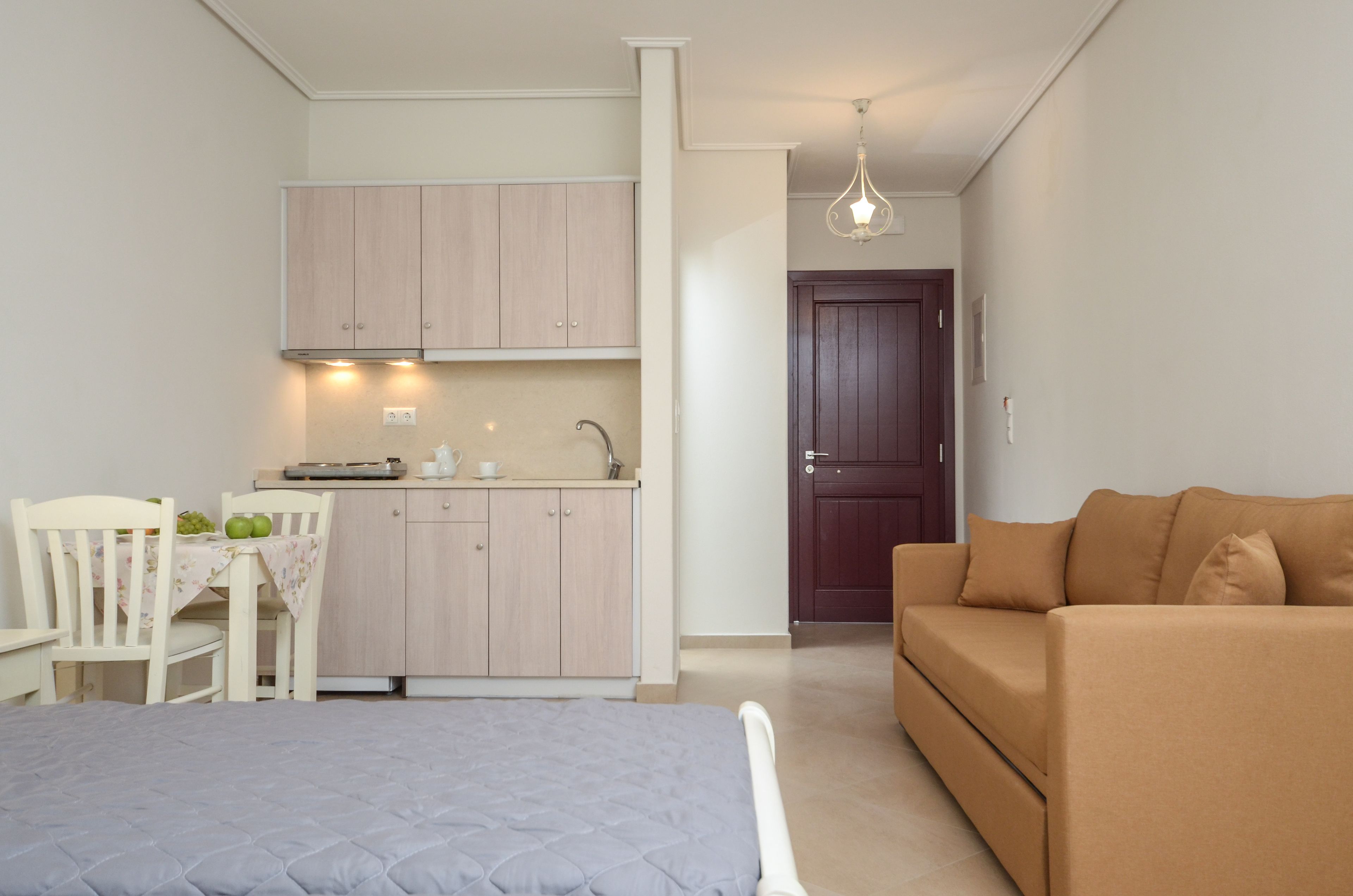 En kompakt bolig med tekøkken, spiseplads og sofa.