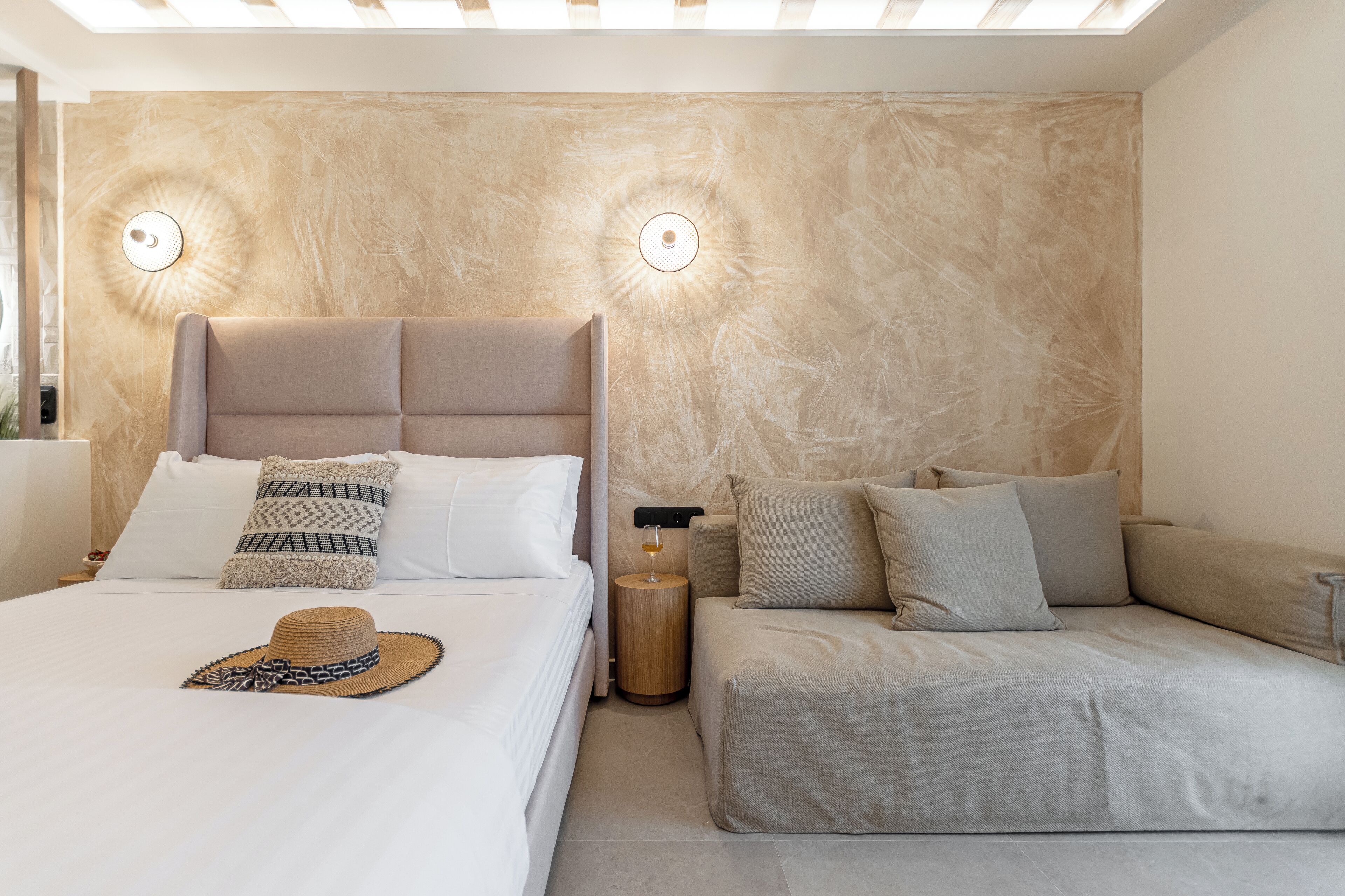 A modern bedroom with a bed, a sofa, and two wall-mounted lights.