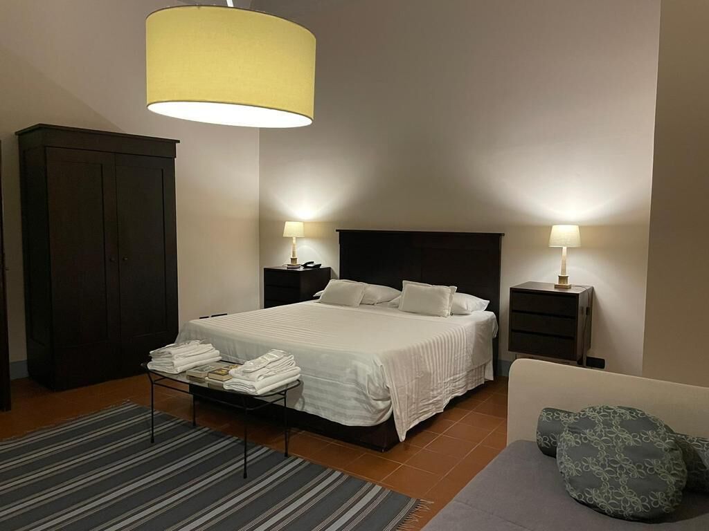 Een keurig opgemaakt slaapkamer met een bed, nachtkastjes, een kledingkast en een slaapbank.
