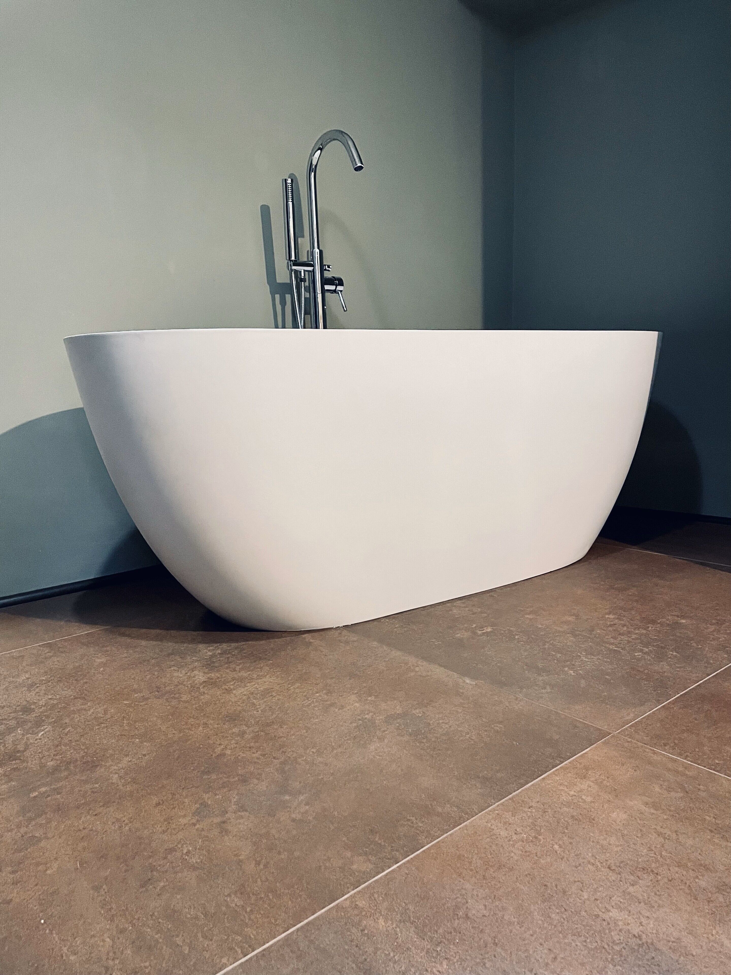 Ein modernes Badezimmer mit freistehender Badewanne, einem Wandarmaturen und einem gefliesten Boden.