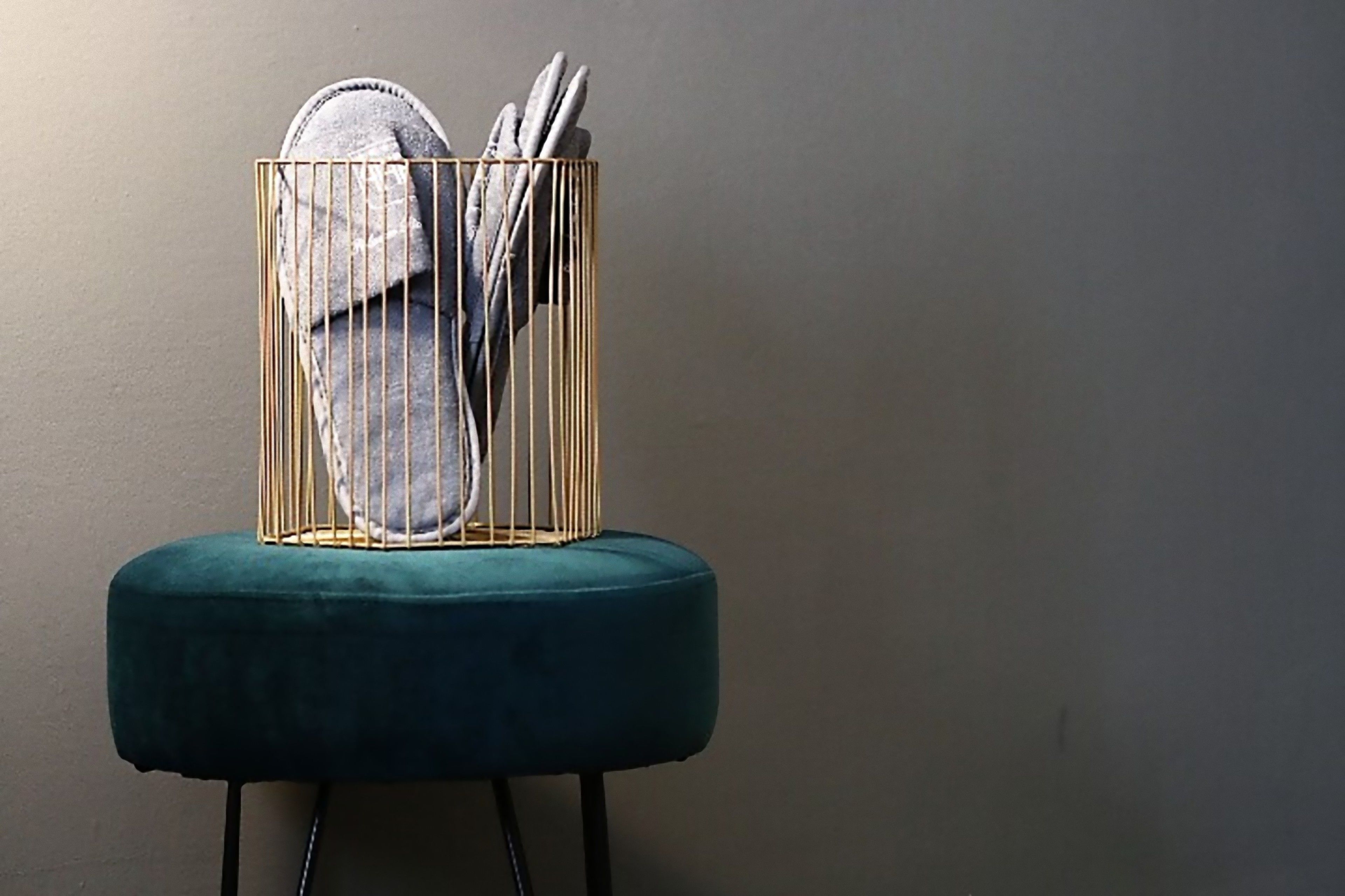 A chair with a gold wireframe basket containing a pair of shoes and a pair of scissors.