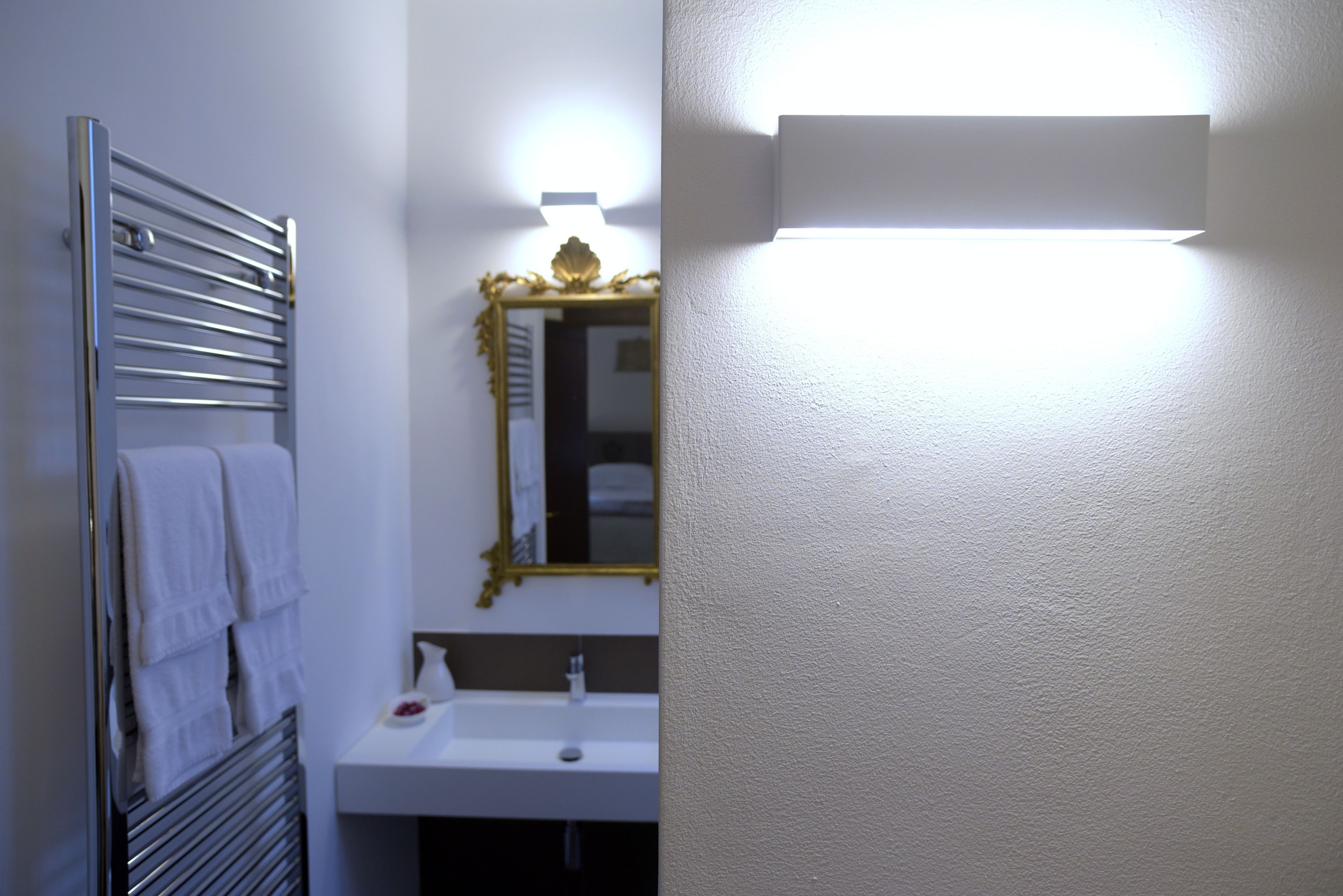 A bathroom with a towel rack, sink, and mirror.