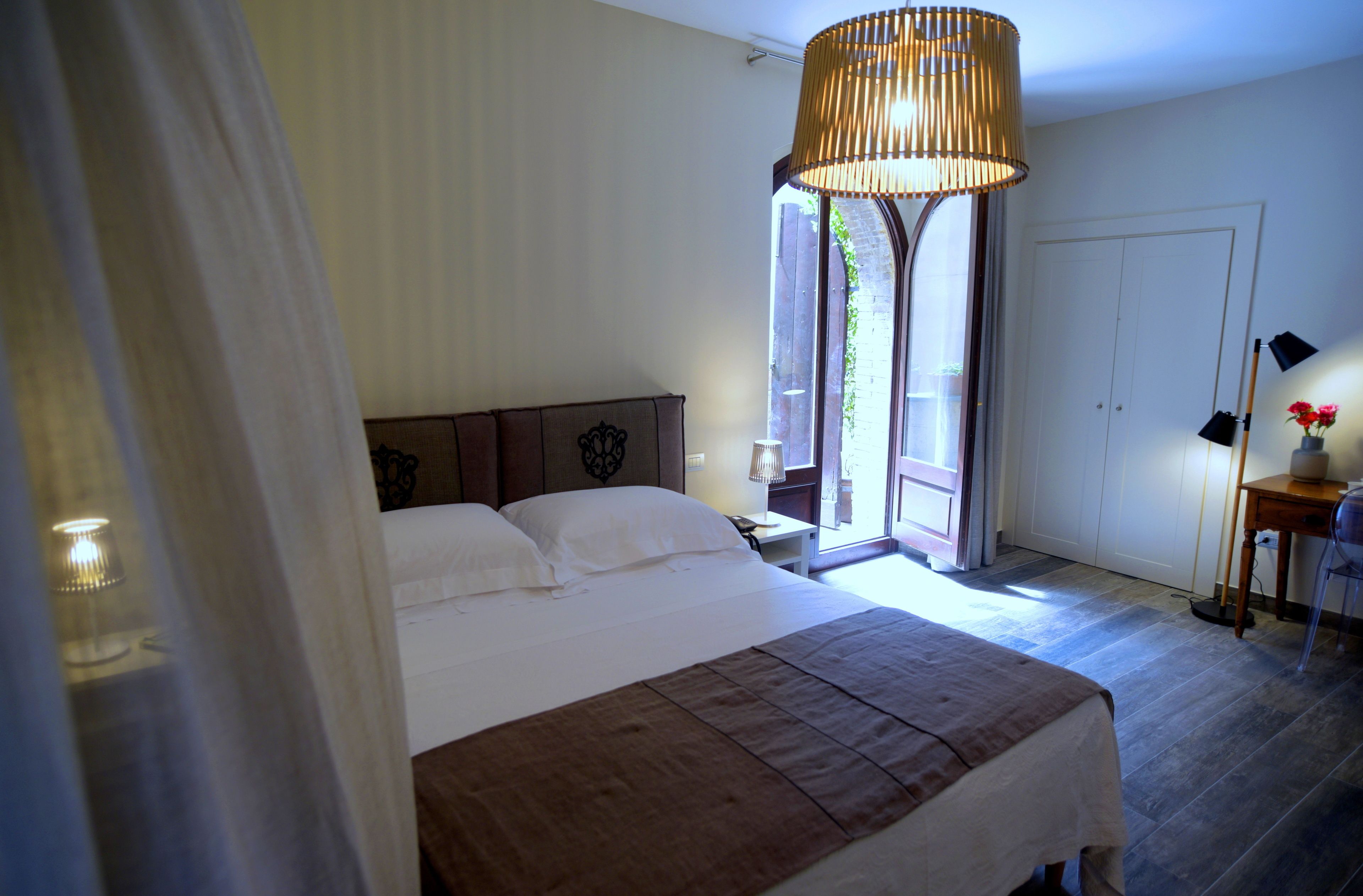 Una camera da letto con un letto grande, una lampada a sospensione, un comodino con lampada e vista sull'esterno.