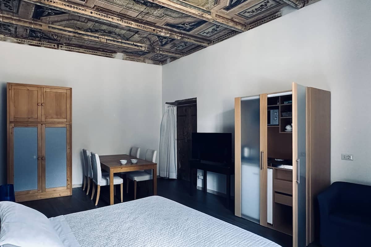 Ein Schlafzimmer mit einem Bett, einem Holzschrank, einem Schreibtisch mit Stühlen und einem Fernseher.