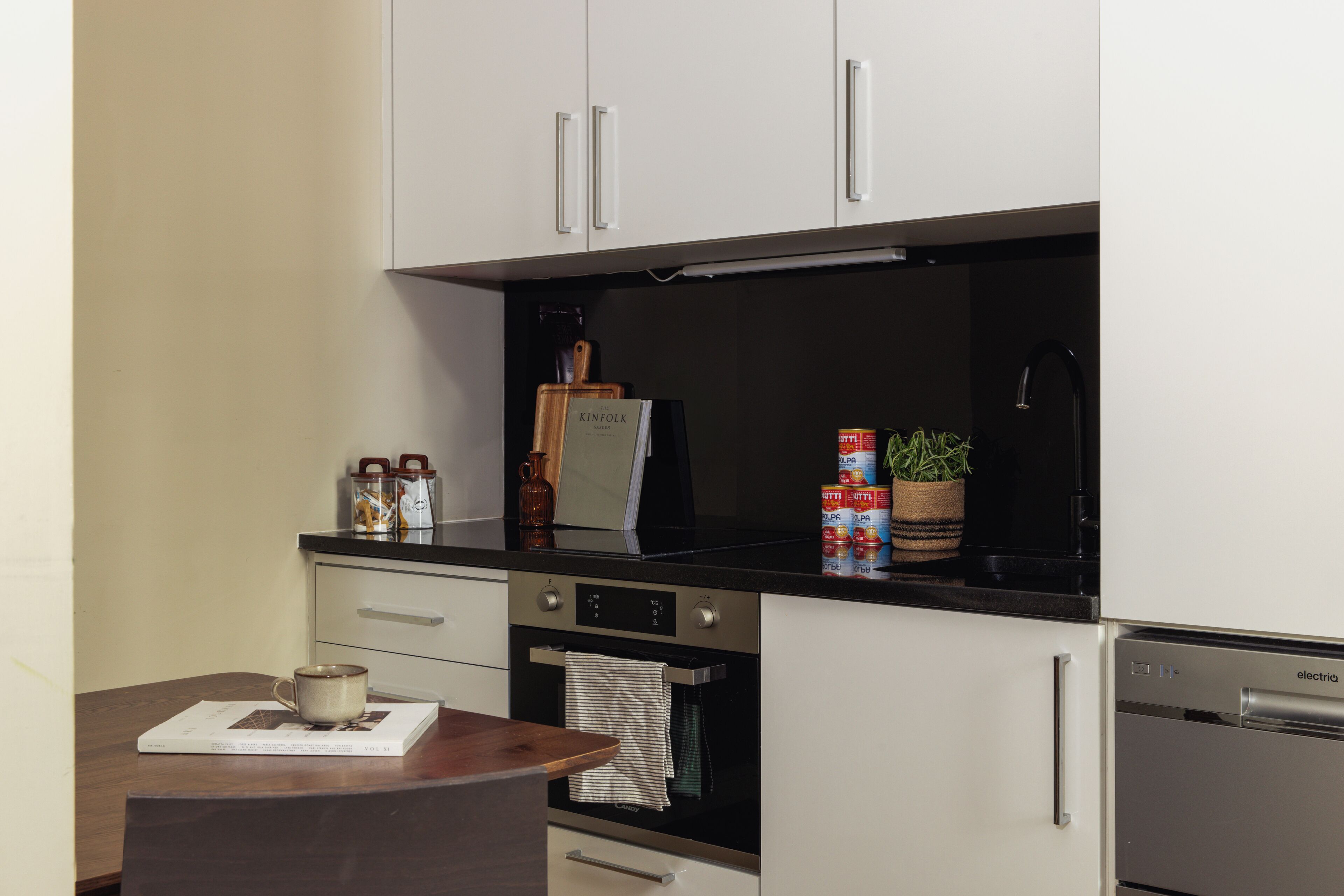 A kitchen with white cabinets, a black countertop, and stainless steel appliances.