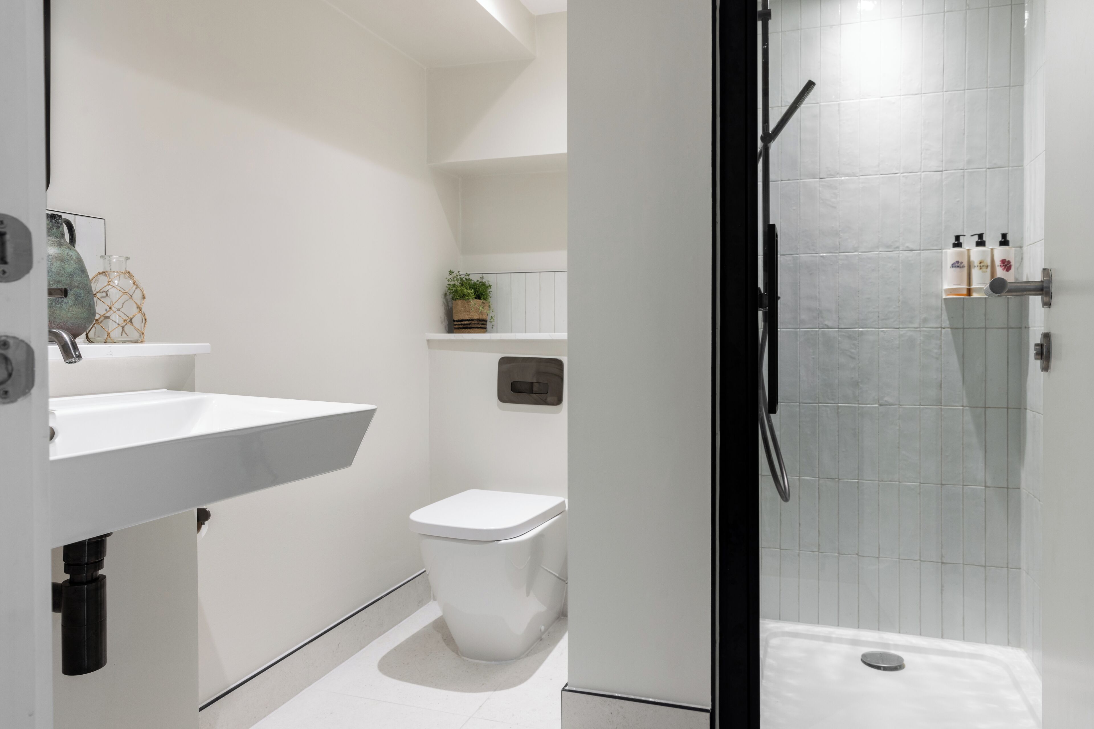 Ein modernes Badezimmer mit Waschbecken, Toilette und Duschbereich in Weiß.