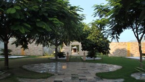Un patio con un sendero de piedra que conduce a la entrada de un edificio, rodeado de árboles y un césped bien cuidado.