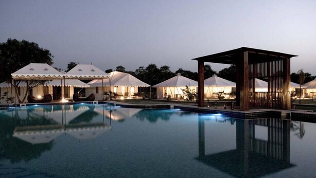 Una piscina con tiendas de campaña y una estructura de madera, probablemente parte de un resort.