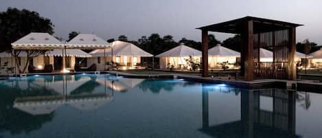 Una piscina al aire libre, sombrillas, sillones reclinables de piscina