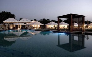 Una piscina con tiendas de campaña y una estructura de madera, probablemente parte de un resort.