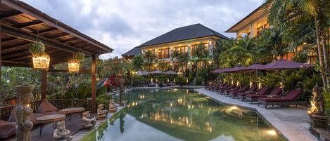 A pool area with lounge chairs, a pergola, and statues.