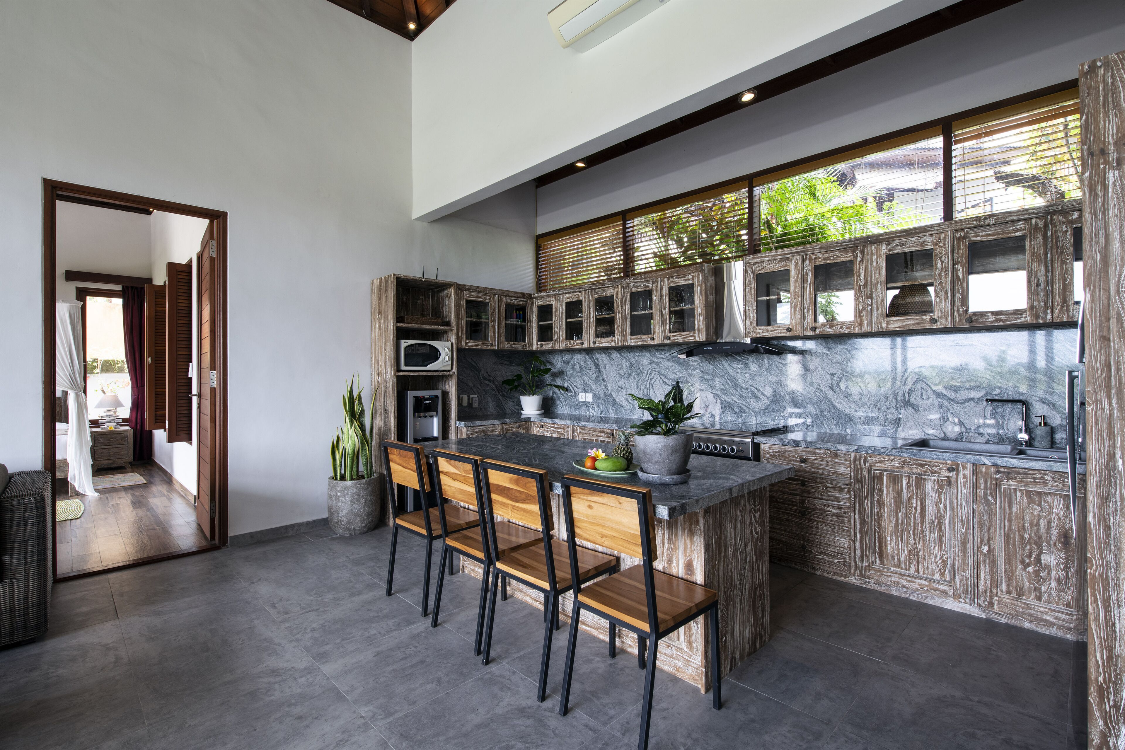 A modern kitchen with a marble countertop, wooden cabinets, and a built-in island with bar stools.