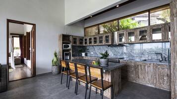 A modern kitchen with a marble countertop, wooden cabinets, and a built-in island with bar stools.