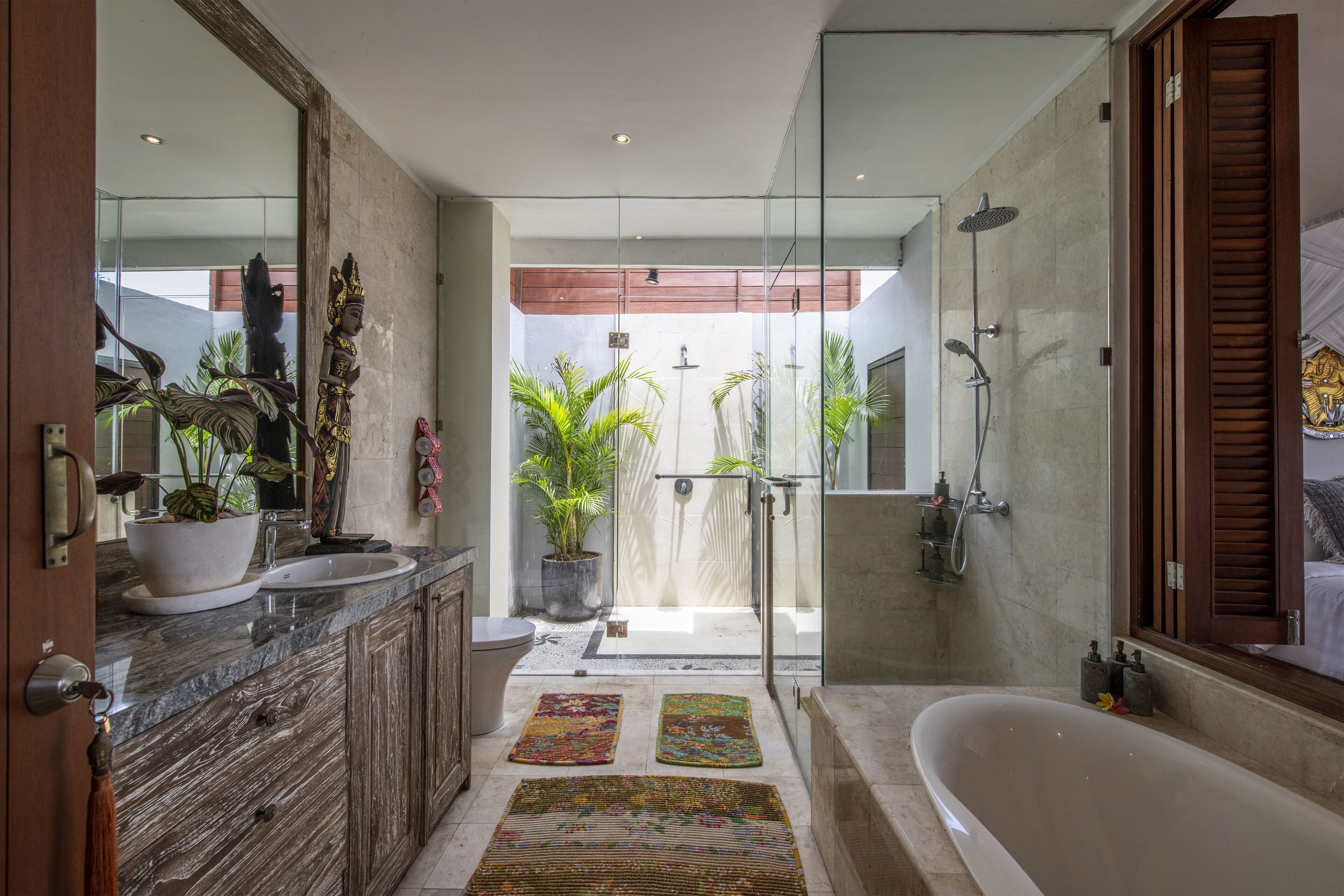 A modern bathroom with a large bathtub, a glass-enclosed shower, and a vanity with a marble countertop.