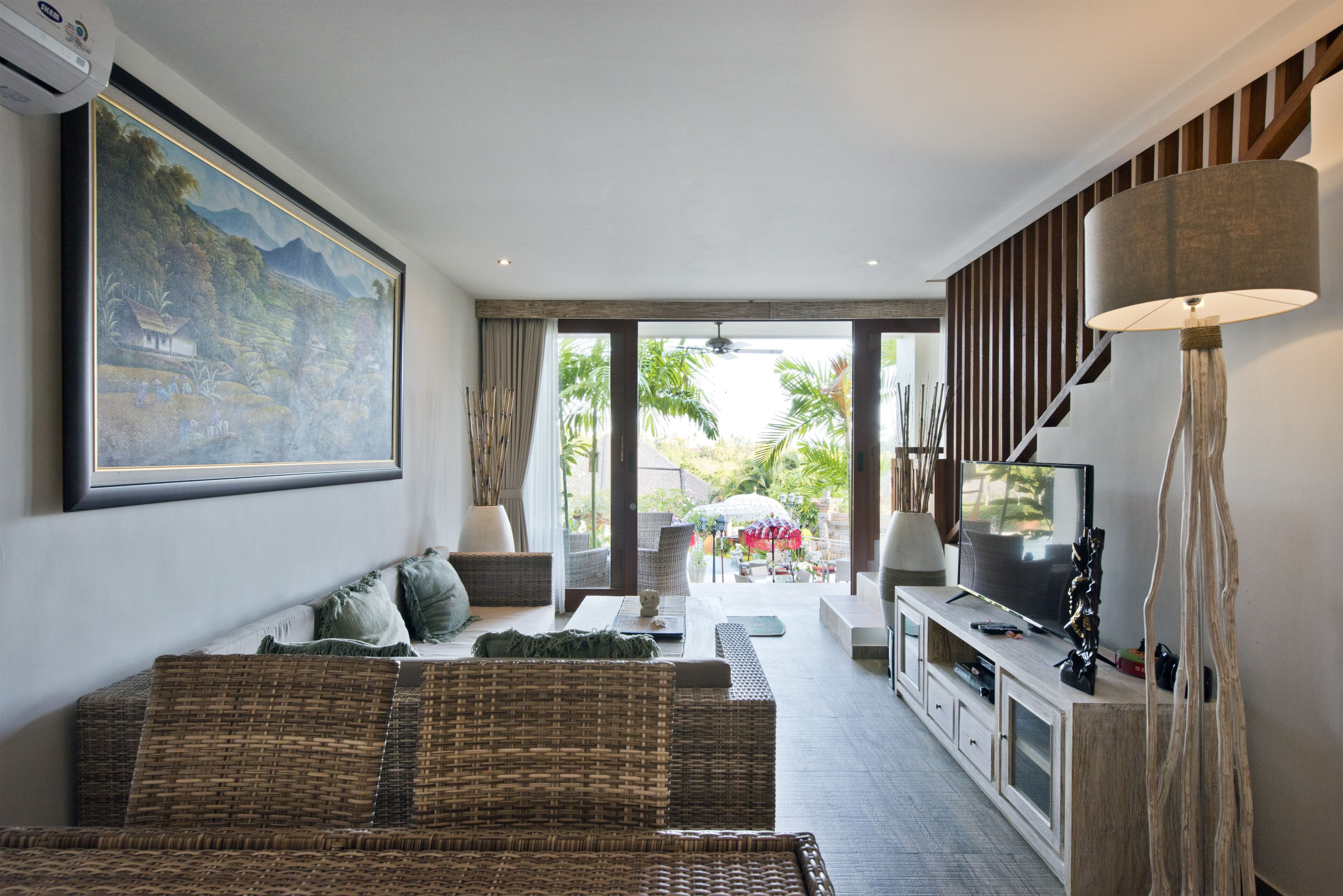 A living room with a sofa, TV, and a painting on the wall.