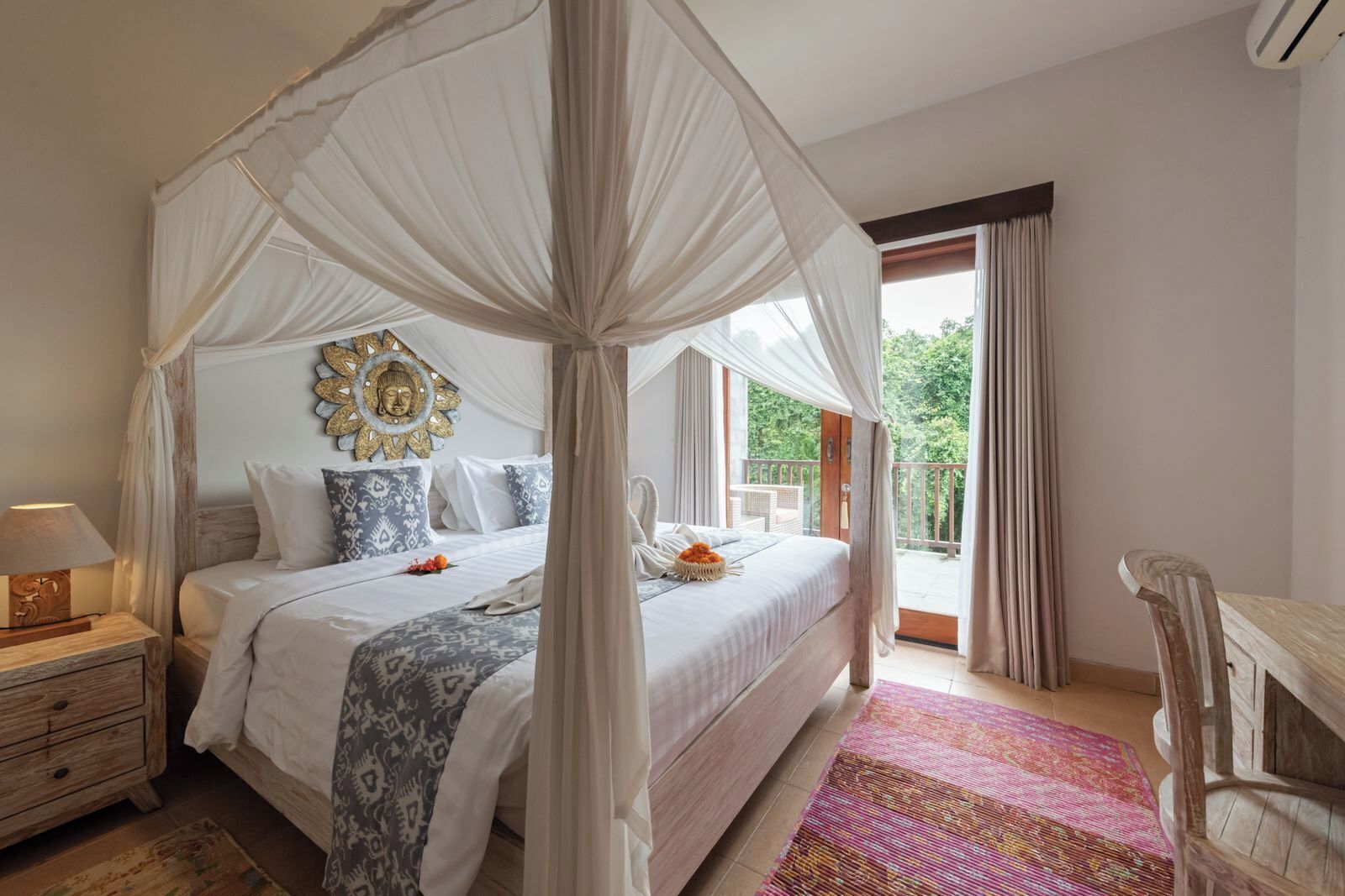 A bedroom with a four-poster canopy bed, a wooden nightstand, a decorative wall piece, and a view of the outdoors.