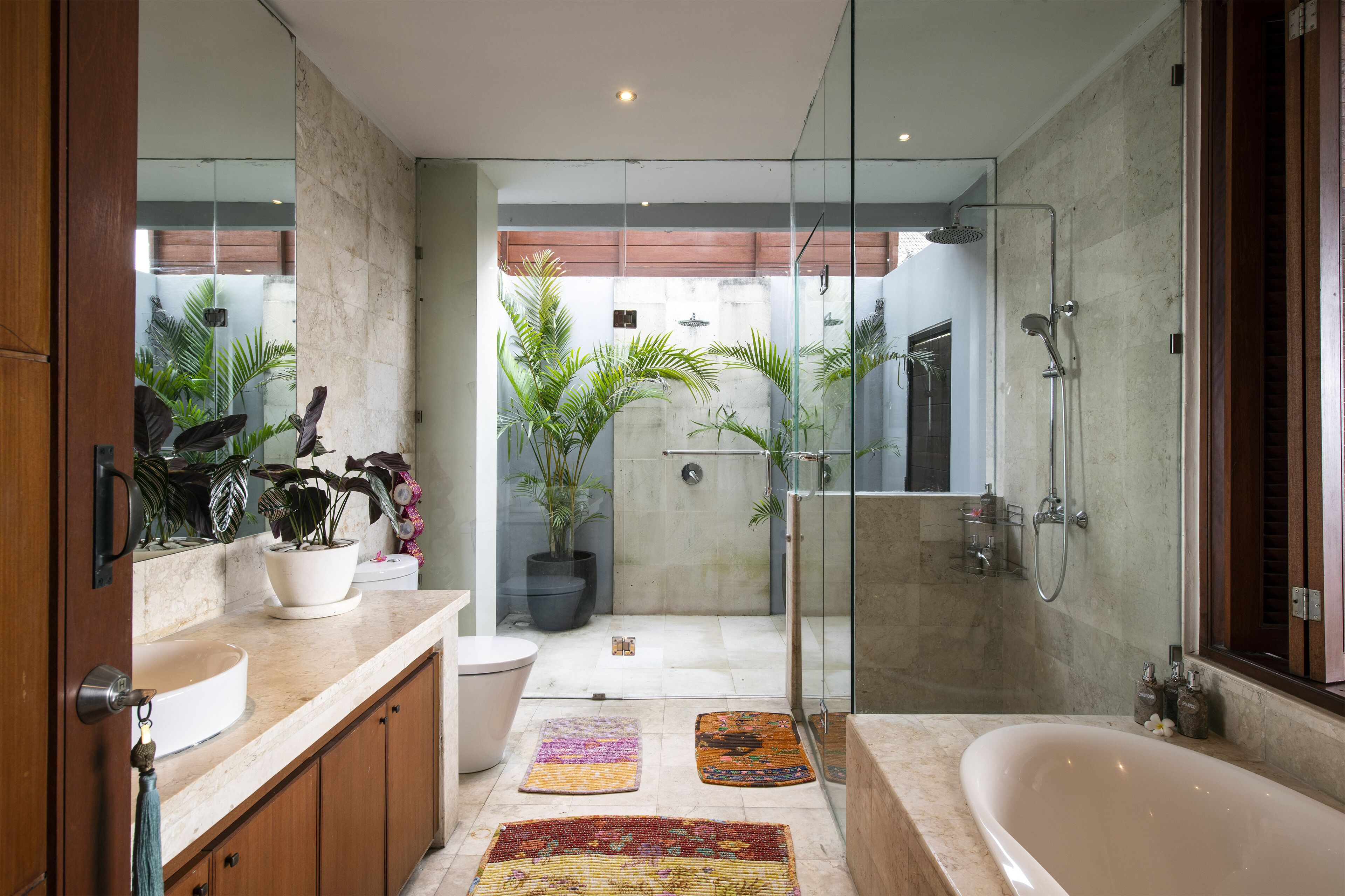Une salle de bain moderne dotée d’une douche à parois de verre, d’une grande baignoire et d’un meuble-lavabo avec un évier et un miroir.
