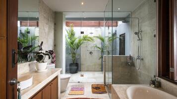Une salle de bain moderne dotée d’une douche à parois de verre, d’une grande baignoire et d’un meuble-lavabo avec un évier et un miroir.