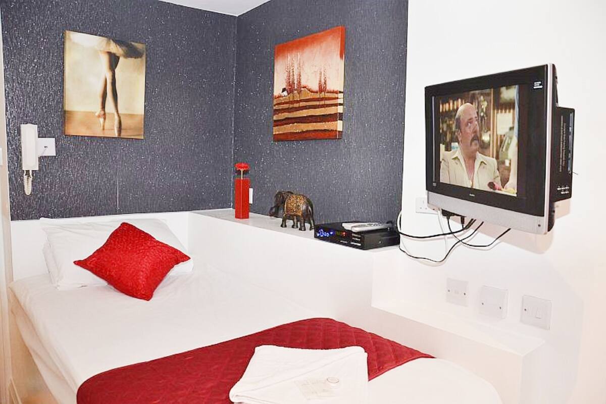 Ein Hotelzimmer mit Bett, Fernseher und Bildern an den Wänden.