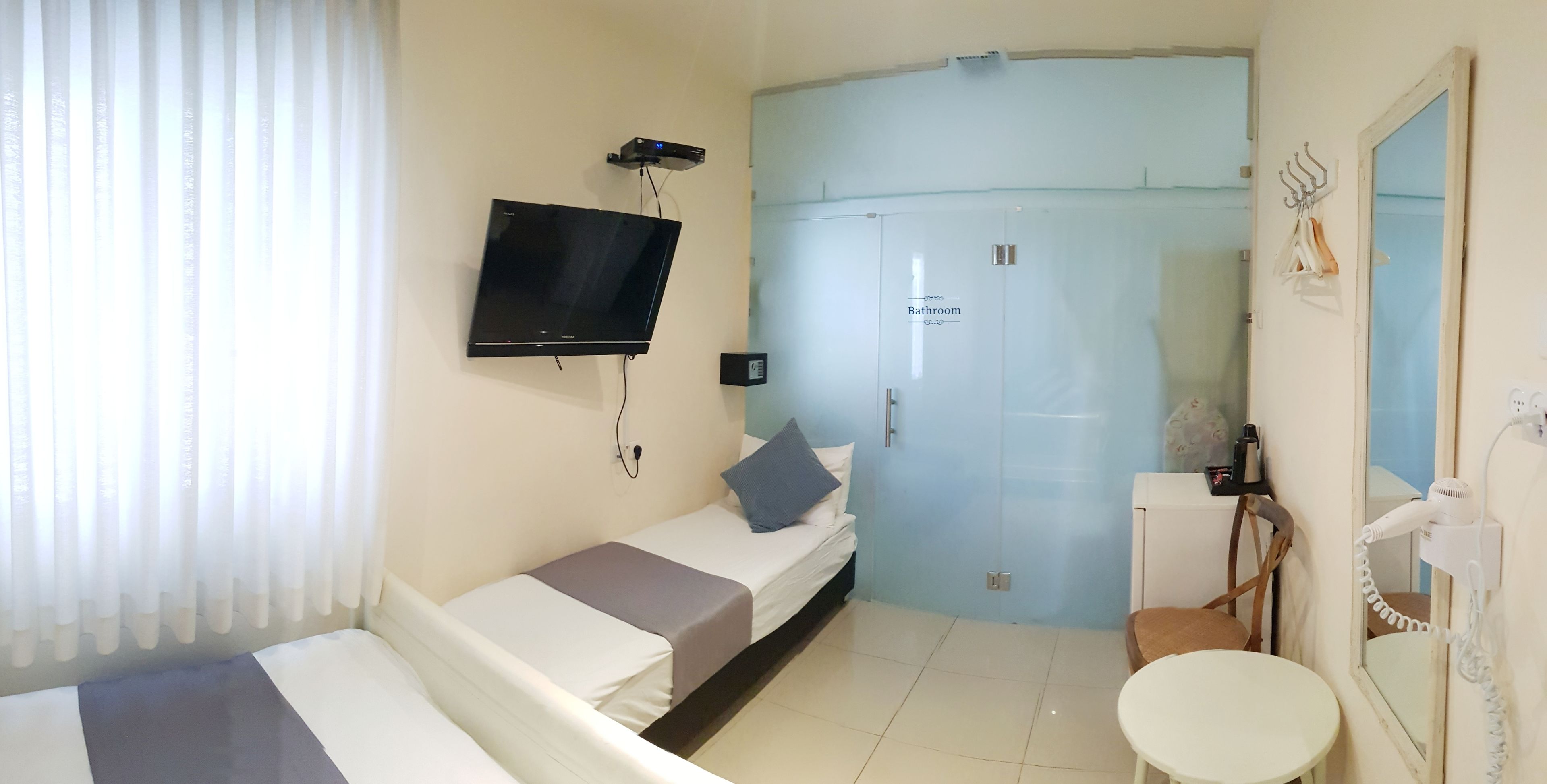 Een hotelkamer met een bed, een tv aan de muur, een badkamers deur en een klein tafeltje.