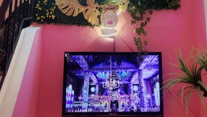A wall with a neon sign saying "Good Coffee Only" and a decorative wall hanging with various plants and flowers. - Central Hotel (Tel Aviv)