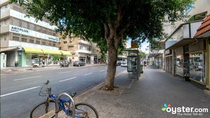 Straßenansicht mit dem Hotel ARTPLUS HOTEL, einer Bushaltestelle und einem Fahrrad, das am Straßenrand steht.